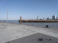 a view of a lighthouse, water and a walkway in the middle of a city