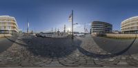 a fisheye lens view of several ships docked at a pier near buildings and flags