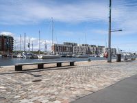 a wooden bench and the harbor, in a small city area with sailboats and boats