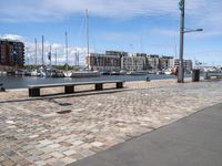 a wooden bench and the harbor, in a small city area with sailboats and boats