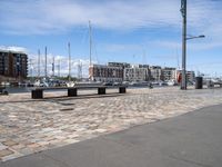 a wooden bench and the harbor, in a small city area with sailboats and boats