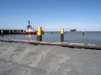 there is an empty port area with two boats in the distance and some barrels out by