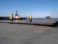 there is an empty port area with two boats in the distance and some barrels out by