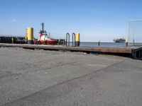 there is an empty port area with two boats in the distance and some barrels out by