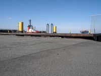 there is an empty port area with two boats in the distance and some barrels out by