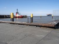 there is an empty port area with two boats in the distance and some barrels out by