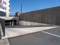 a wall and two fences along the side of a road next to a parking area