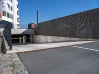 a wall and two fences along the side of a road next to a parking area