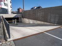 a wall and two fences along the side of a road next to a parking area