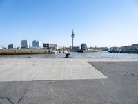 an empty parking lot with a view of the city in the background with water, a boat and boats