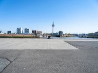 an empty parking lot with a view of the city in the background with water, a boat and boats