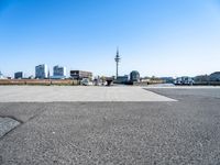 an empty parking lot with a view of the city in the background with water, a boat and boats