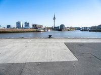 an empty parking lot with a view of the city in the background with water, a boat and boats