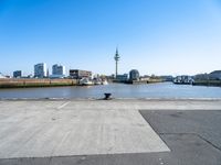 an empty parking lot with a view of the city in the background with water, a boat and boats