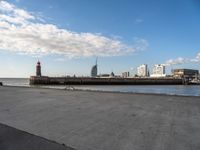 a road in between the sky and some buildings with a red tower in the middle