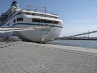 large white boat docked at a port with a rope on it's end and other boats in the water