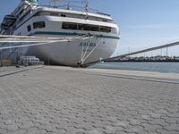 large white boat docked at a port with a rope on it's end and other boats in the water