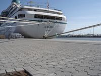 large white boat docked at a port with a rope on it's end and other boats in the water