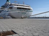 large white boat docked at a port with a rope on it's end and other boats in the water