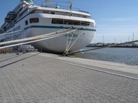 large white boat docked at a port with a rope on it's end and other boats in the water