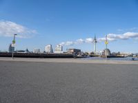 the skyline is in the background from the street where the water meets the shoreline of a river