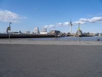 the skyline is in the background from the street where the water meets the shoreline of a river