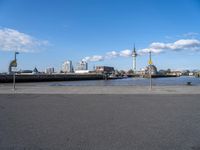 the skyline is in the background from the street where the water meets the shoreline of a river