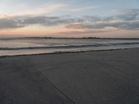 a person on a skate board skating in front of the ocean at sunset during a cloudy day