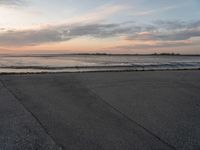 a person on a skate board skating in front of the ocean at sunset during a cloudy day