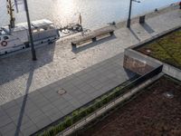 several benches and a boat are sitting on a lake shore with water behind them at the docks