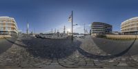 a fisheye lens view of several ships docked at a pier near buildings and flags