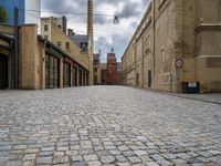 an alleyway with bricks and brick buildings next to a road that has small traffic signs on it