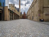 an alleyway with bricks and brick buildings next to a road that has small traffic signs on it