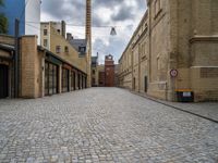 an alleyway with bricks and brick buildings next to a road that has small traffic signs on it