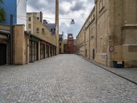 an alleyway with bricks and brick buildings next to a road that has small traffic signs on it