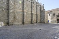 a stone area with a brick building and brick walkway in the background and light grey cobblestones