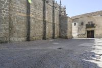 a stone area with a brick building and brick walkway in the background and light grey cobblestones