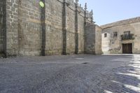 a stone area with a brick building and brick walkway in the background and light grey cobblestones