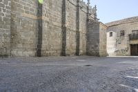 a stone area with a brick building and brick walkway in the background and light grey cobblestones