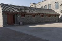 a brick building with an attached roof and a door that reads chinese language written below