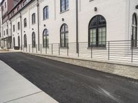 a person is riding a skateboard on the sidewalk near an old brick building while another passes by