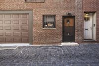 a building with a brick sidewalk and garage door in front of it and windows that have bars on them