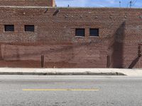 a fire hydrant sitting next to a brick building on a street corner with a side walk in front