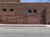 a fire hydrant sitting next to a brick building on a street corner with a side walk in front