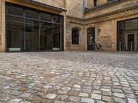 an outdoor area with bicycle parked next to large windows and brick building frontage with large glass walls