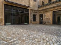 an outdoor area with bicycle parked next to large windows and brick building frontage with large glass walls