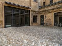 an outdoor area with bicycle parked next to large windows and brick building frontage with large glass walls