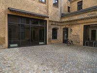 an outdoor area with bicycle parked next to large windows and brick building frontage with large glass walls