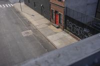 a street view looking down on a large brick building and two windows with graffiti on the side and the bottom