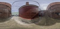 two large red pipes with one empty cylinder in the center of them in the middle of an outside brick building